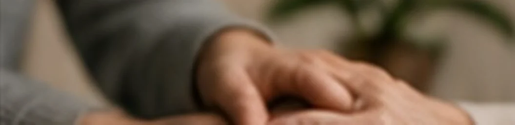Carer holding an older person's hand to offer comfort during end of life care